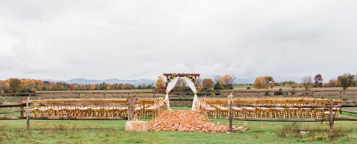 This wedding venue with mountain view has a ceremony set up during the fall in a field.